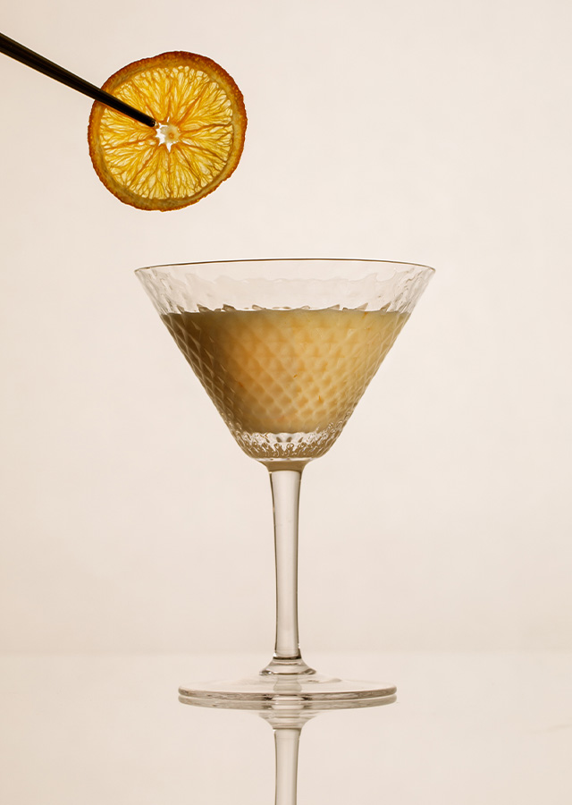 Cocktailglas mit einem Getränk und einer Orangenscheibe an einem Spieß darüber