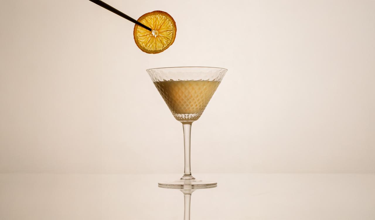 Cocktailglas mit einem Getränk und einer Orangenscheibe an einem Spieß darüber