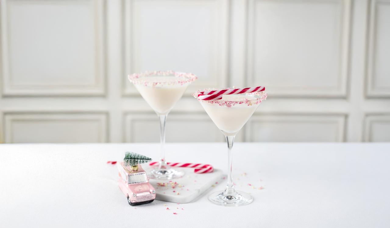 Zwei Martini-Gläser mit weißem Getränk und Zuckerrand, daneben ein Miniaturauto mit kleinem Weihnachtsbaum und zwei Zuckerstangen